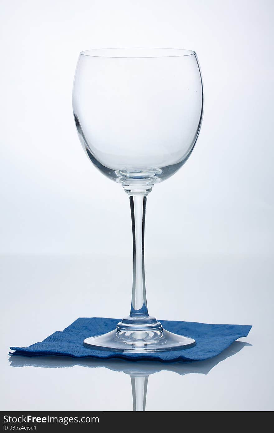 Empty wine glass on blue napkin reflected on table