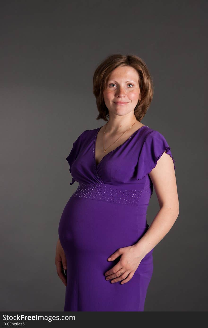 Beautiful pregnant woman staing on grey background