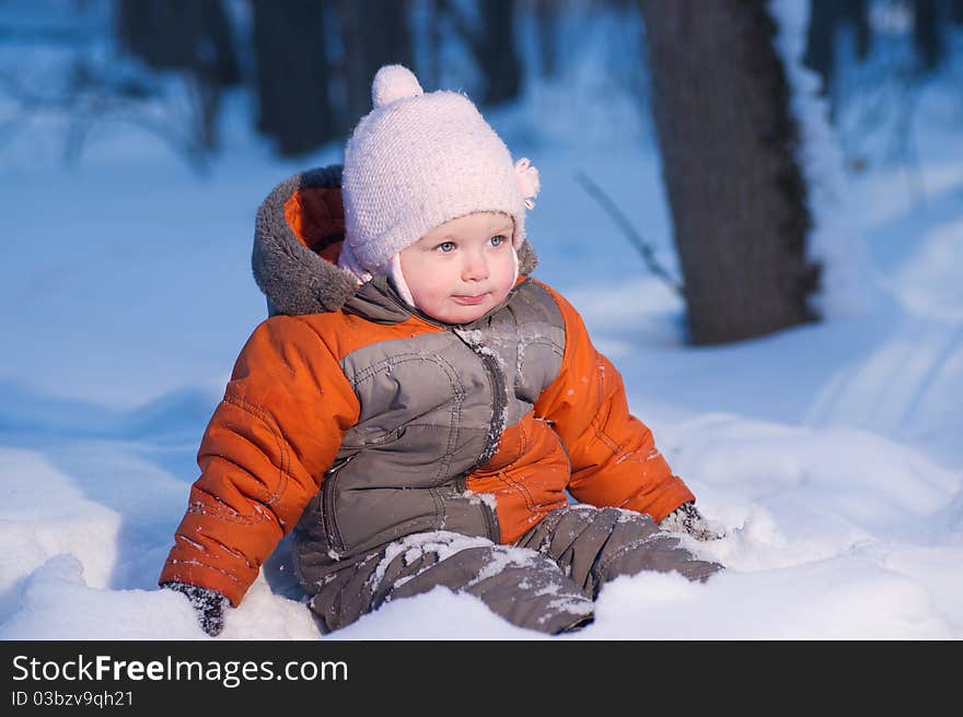 Adorable baby sit in deep snow in evening park looking forward. Adorable baby sit in deep snow in evening park looking forward