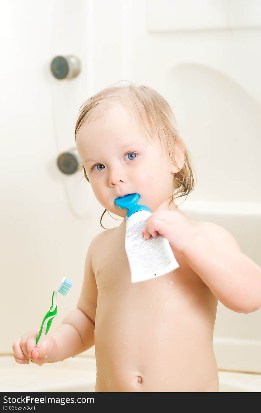 Adorable baby brushing teeth in shower