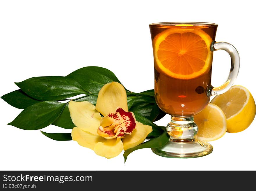 Tea in a glass glass, a lemon, flowers on the white isolated background