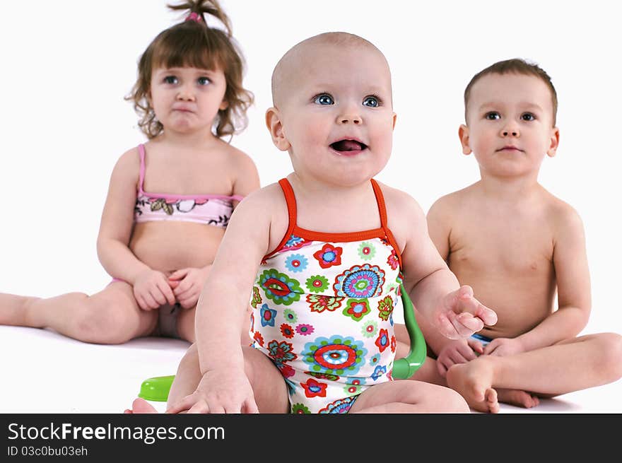 Two girls and one boy in swimsuit white background.Three small children play with toys. Two girls and one boy in swimsuit white background.Three small children play with toys.