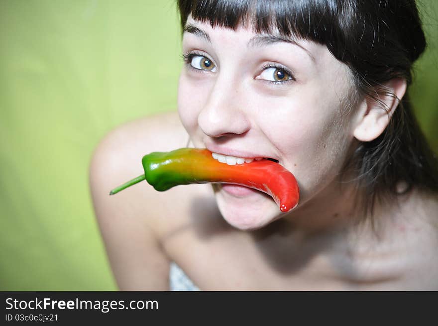 Happy young woman holding hot pepper in her teeth (mouth). Happy young woman holding hot pepper in her teeth (mouth)