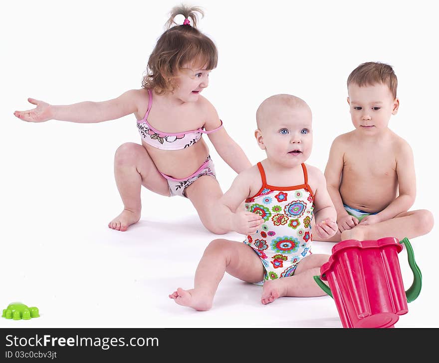 play with toys. Two girls and one boy sitting on a white background. play with toys. Two girls and one boy sitting on a white background.