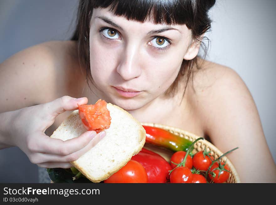 Unhappy woman keeping a diet, eating a tomato. Unhappy woman keeping a diet, eating a tomato