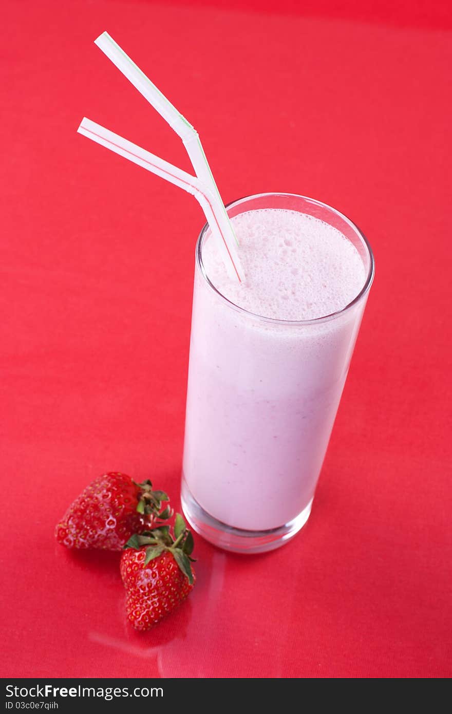 Strawberry milkshake with fresh fruit on red background