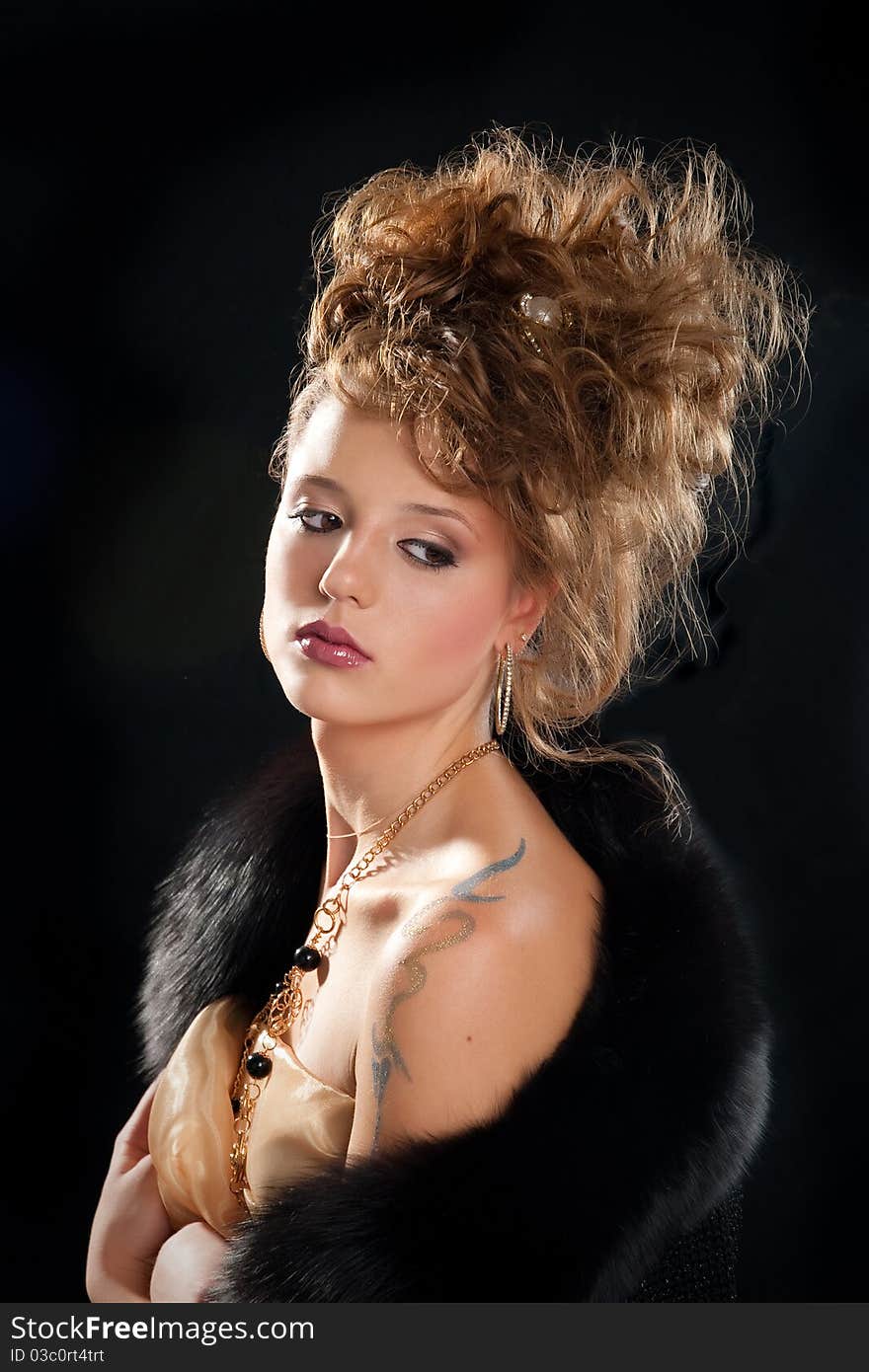 Young woman glamour portrait with a black fur on black studio background. Young woman glamour portrait with a black fur on black studio background