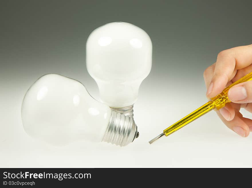 Screwdriver and Light Bulb on White and gray Background. Screwdriver and Light Bulb on White and gray Background