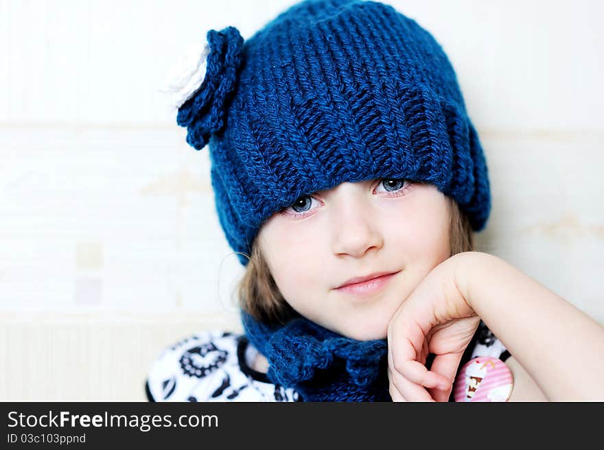 Close-up indoor portrait of lovely child girl wearing blue knitted hat. Close-up indoor portrait of lovely child girl wearing blue knitted hat