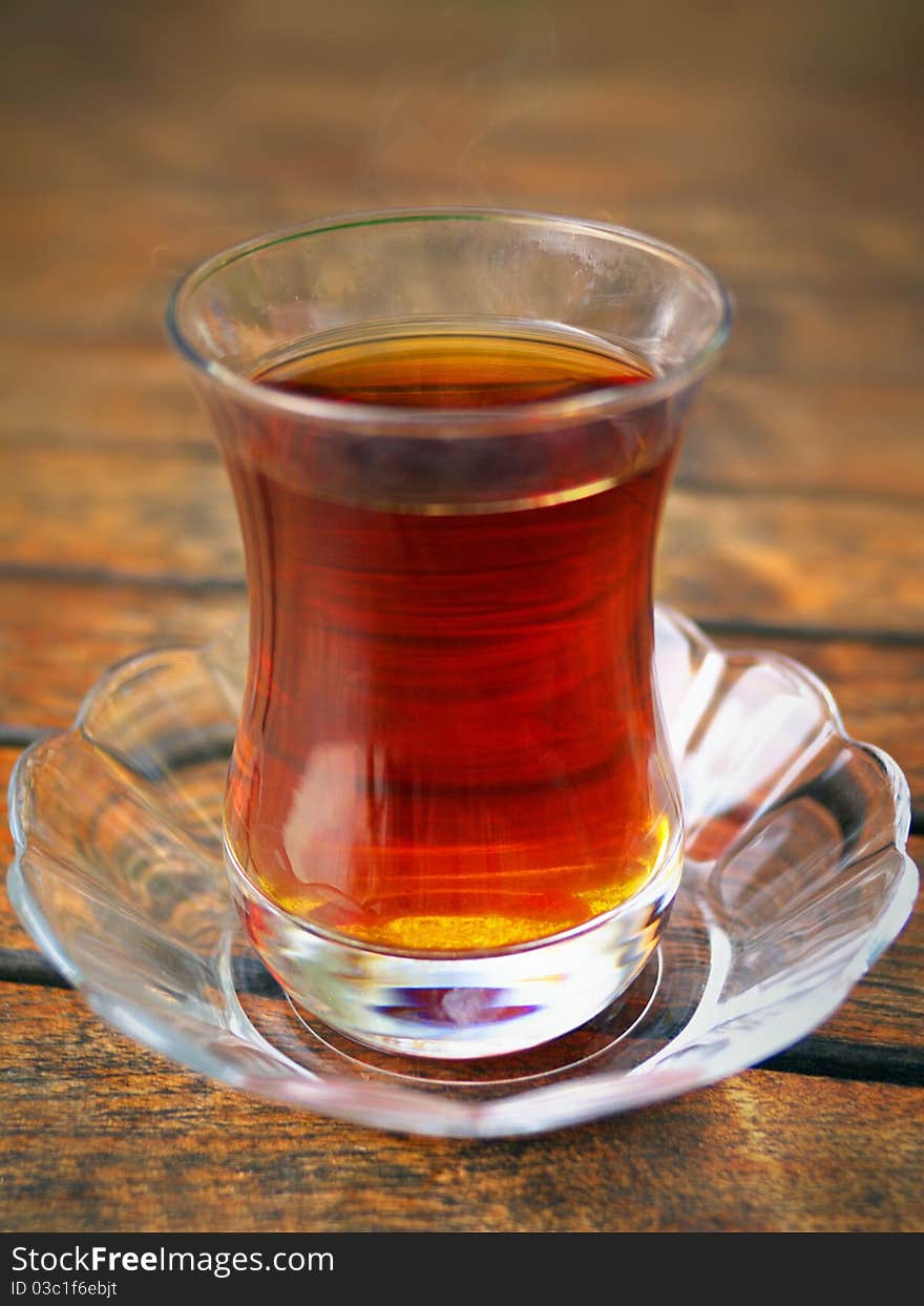 Glass of Turkish tea and saucer on the wooden table. Glass of Turkish tea and saucer on the wooden table