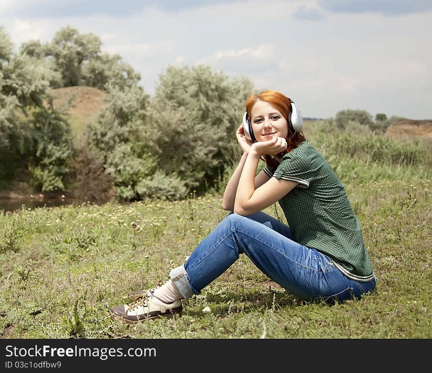 Young fashion girl with headphones at grass in spring time.