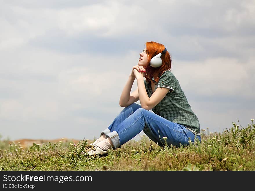 Young fashion girl with headphones at grass in spring time.