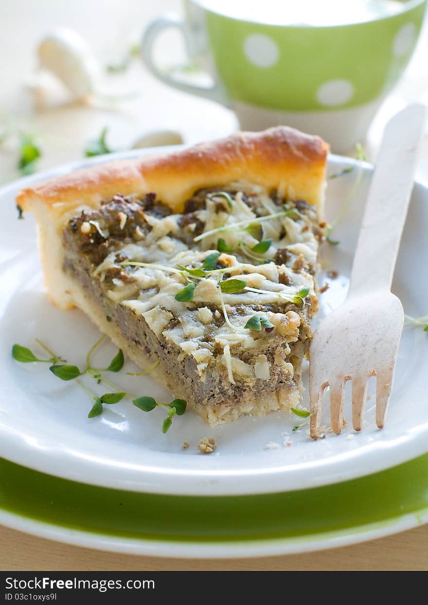 Minced meat pie with cup of chicken stock on background