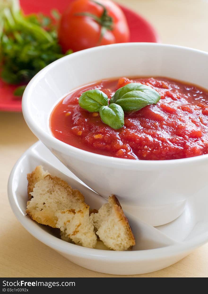 Bowl of tomato soup with bread crouton and basil