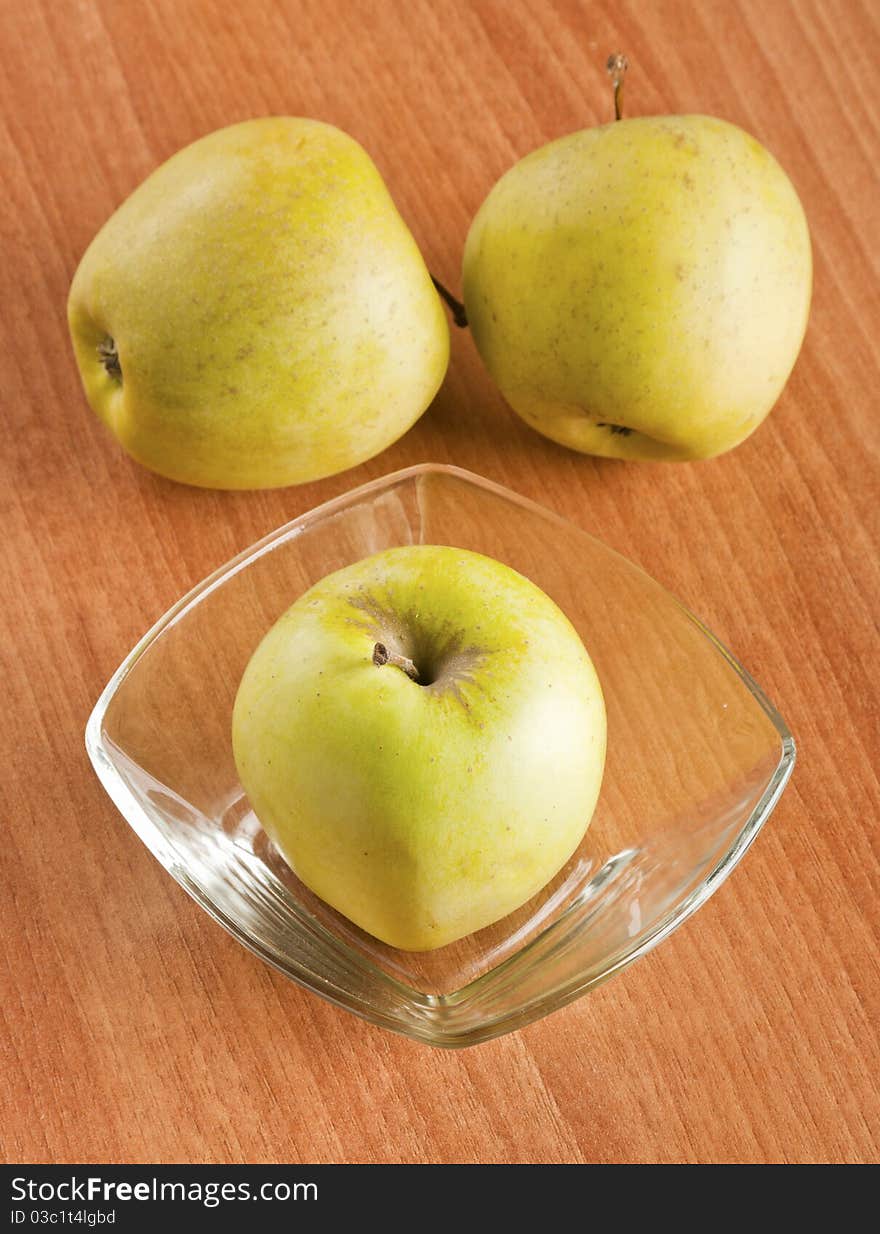 Tree apples in glass boll on a wooden backgtound