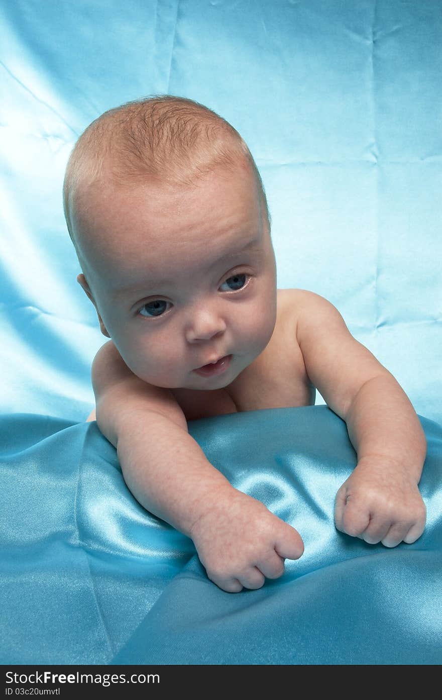 Three month old baby laying on a blue satin sheet. Three month old baby laying on a blue satin sheet