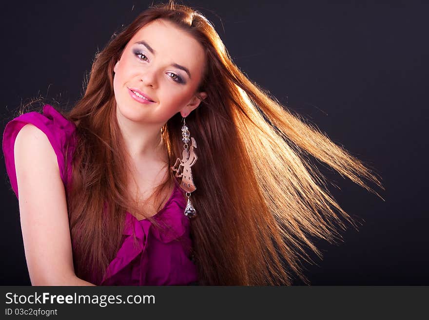 Beautiful long-haired brunette in a dress of fuchsia with sparkle earring. Beautiful long-haired brunette in a dress of fuchsia with sparkle earring