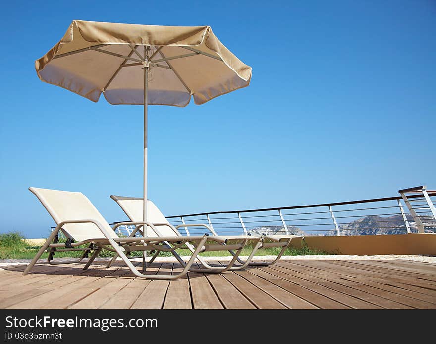 Photo of two deck-chairs with umbrella on the seascape