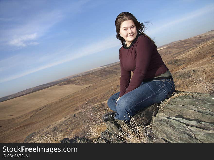 Girl smiles, sits on stones in the autumn. Girl smiles, sits on stones in the autumn.