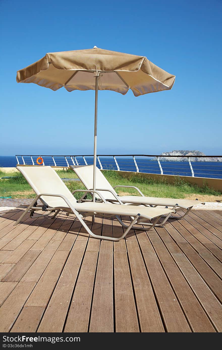 Photo of two deck-chairs with umbrella on the seascape