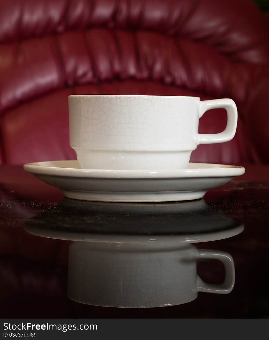 White cup of coffee on Black reflect table and red background