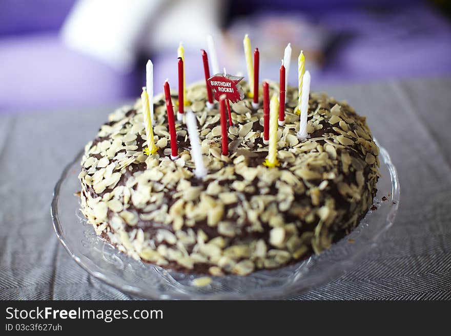 Chocolate birthday cake with almonds and candles on the table