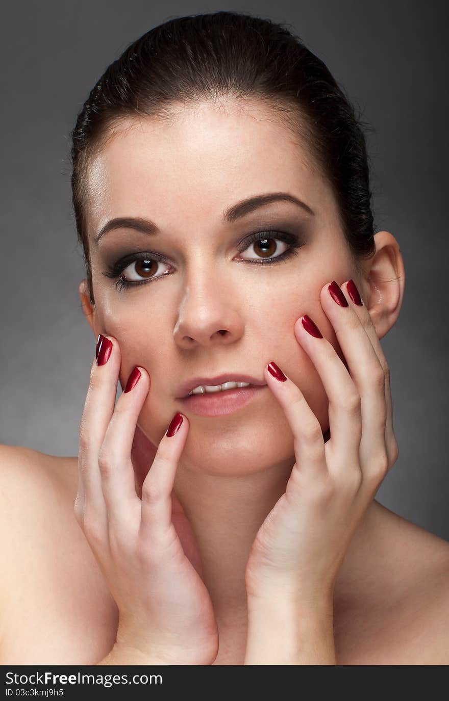 Woman face with red fingernail isolated on gray