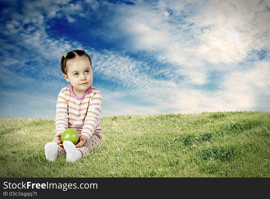 The child with an apple against a green meadow