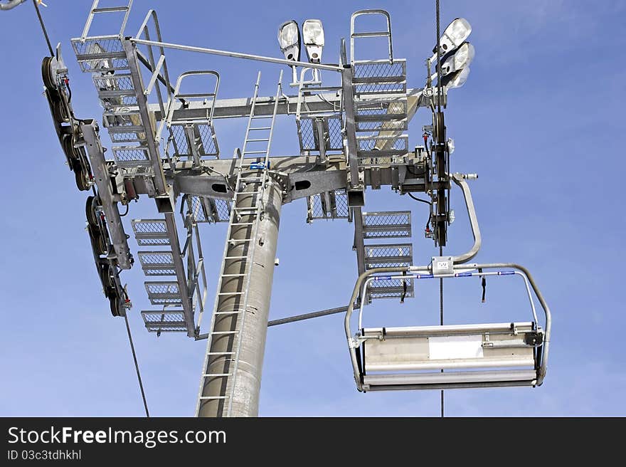 Large cable ski chairlift tower against a blue sky.