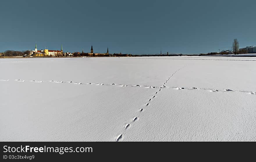 Footprints on the snow over the frozen river in th