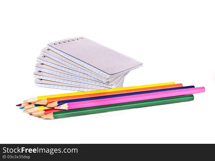 Colored pencils and a pile of notepads. Colored pencils and a pile of notepads