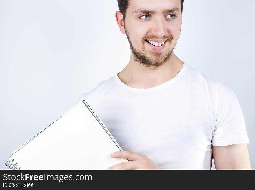 Isolated image of a young blonde man holding a notebook and smiling happily. Isolated image of a young blonde man holding a notebook and smiling happily