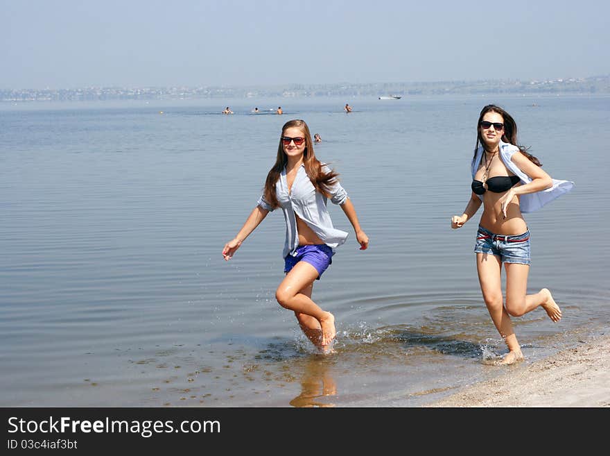 Happy young women running across the beach