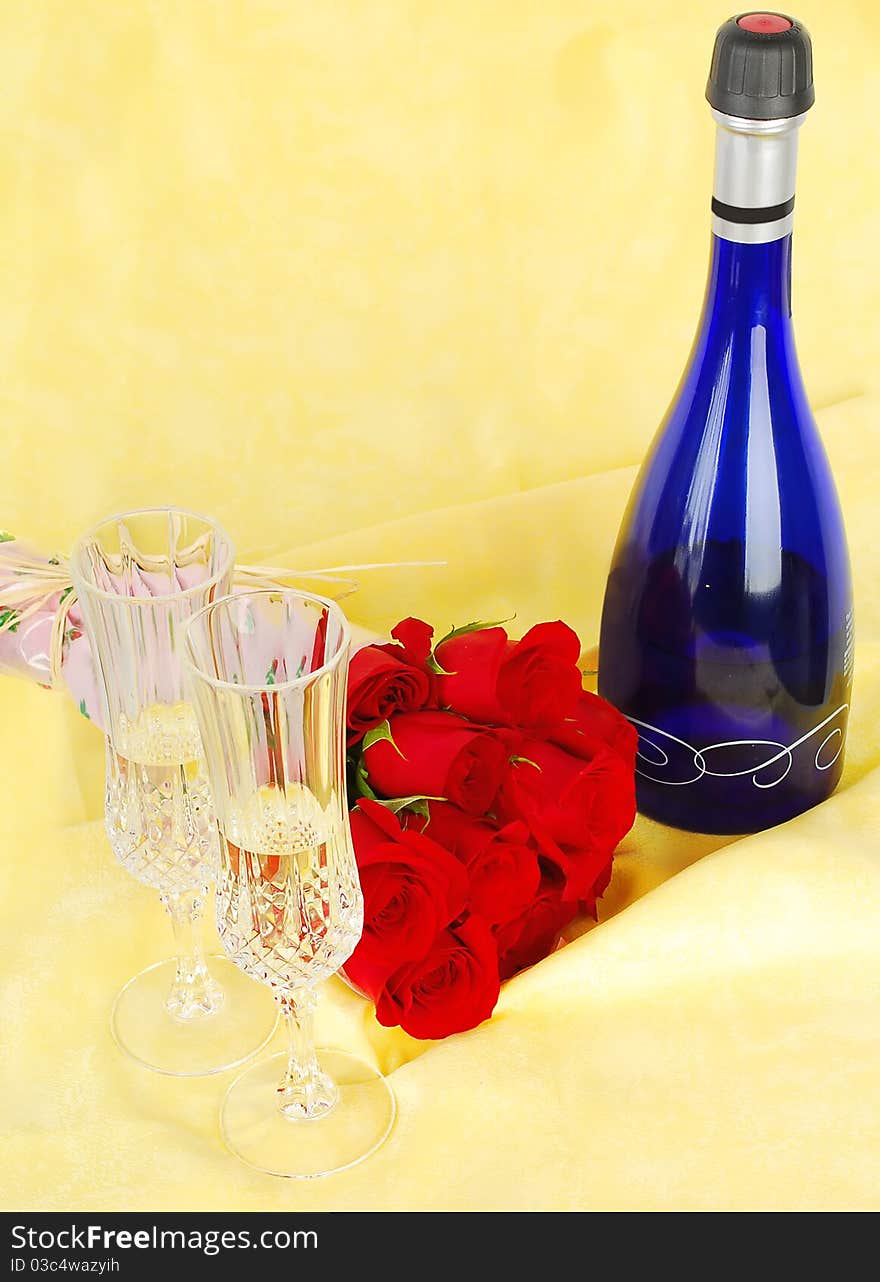 Champagne and roses for celebration of Valentines day with blue bottle on yellow background