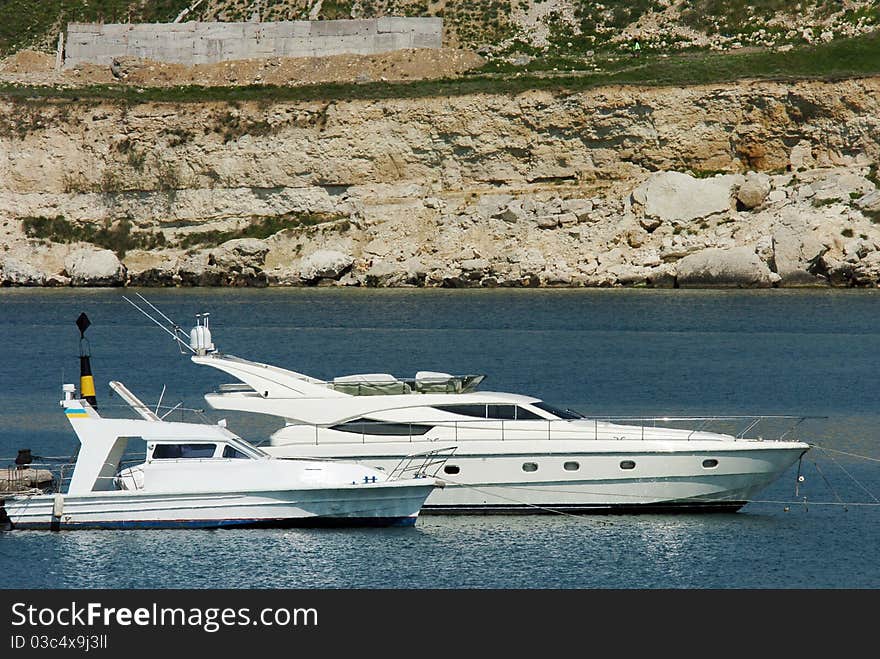 Two boats floating on the sea against the rocks