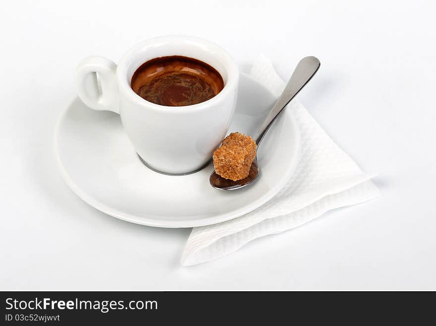 Coffee on a saucer and a spoon with a piece of cane sugar