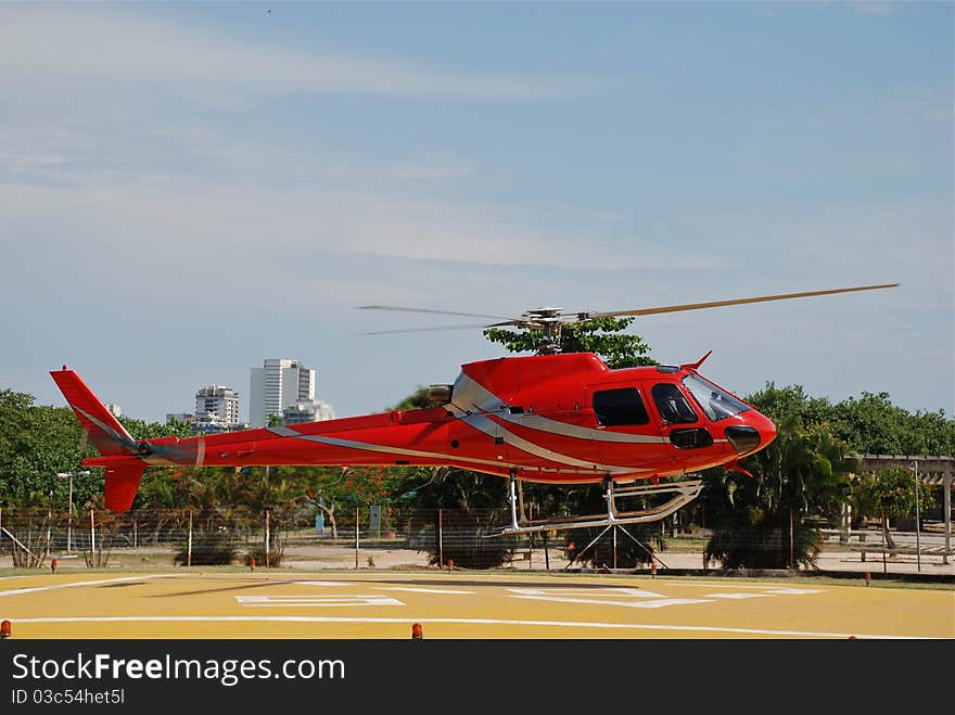 Red helicopter landing on heliport in Rio De Janeiro