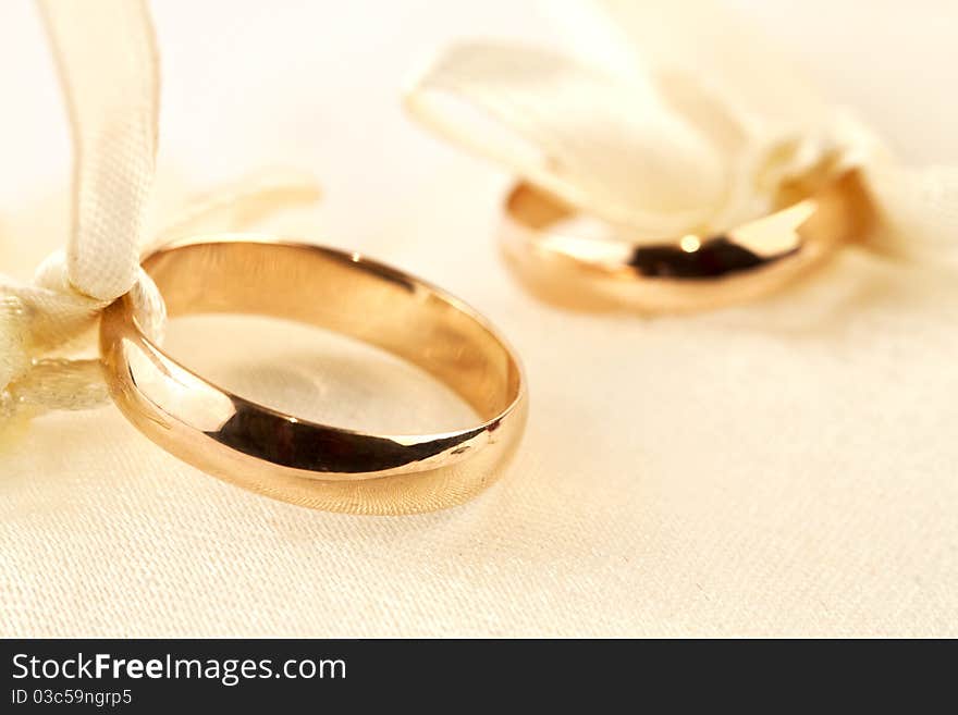 Two gold rings on little pillow. One ring in focus