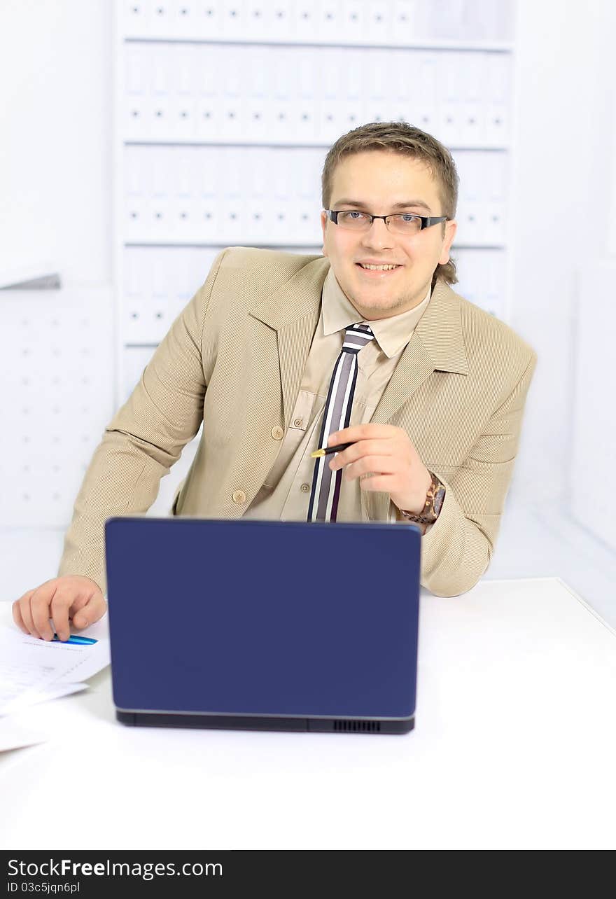 Portrait of businessman using desktop computer, looking at camera