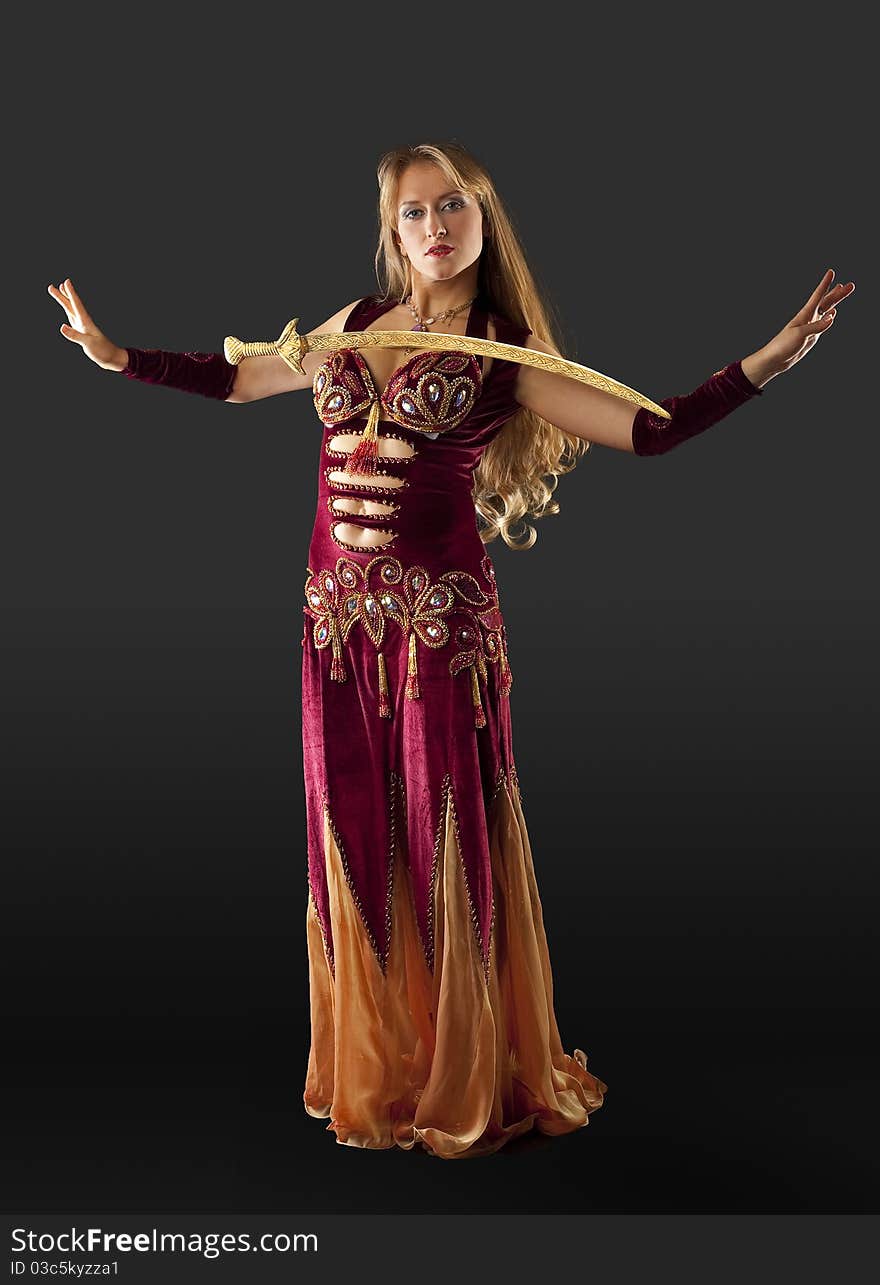 Beauty blond arabian dancer stand with saber on breast