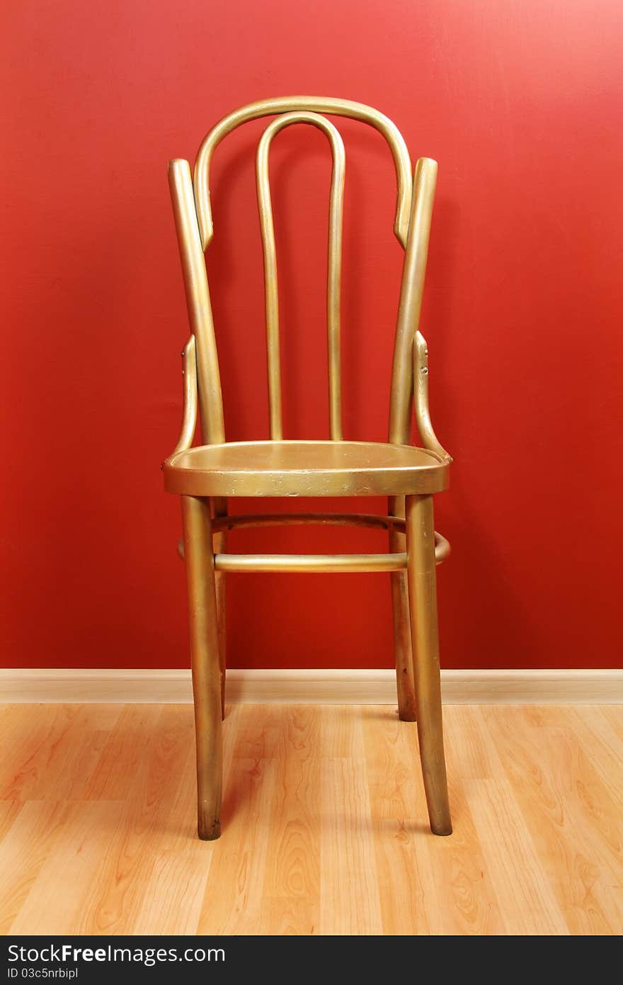 Old-fashioned golden wood chair against red wall