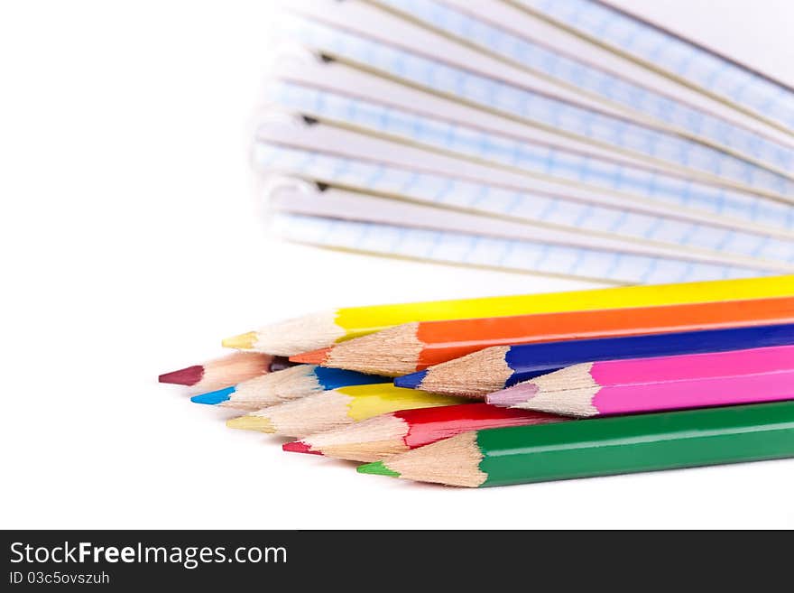 Colored pencils and a pile of notepads. Colored pencils and a pile of notepads