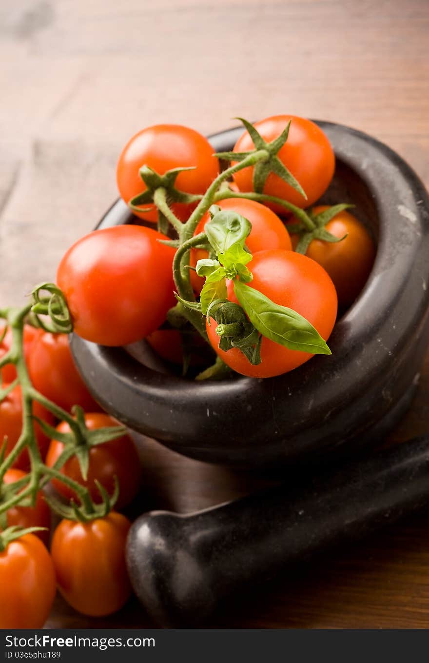 Photo of tomatoes inside a black mortar ready to be smashed for preparing tomatoe sauce