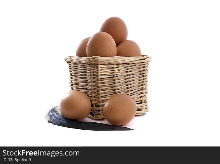 Eggs in basket with feather on the white background