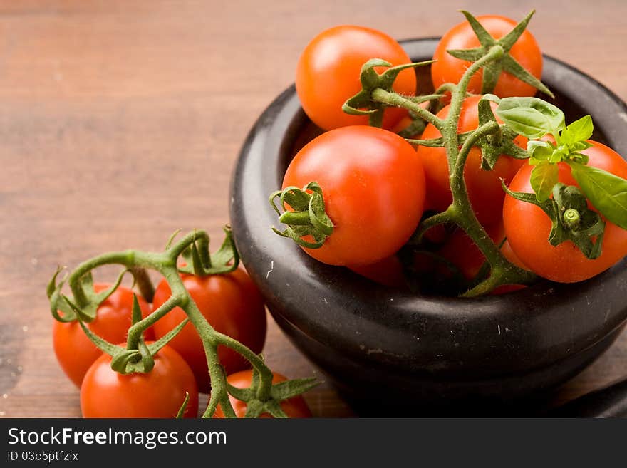 Photo of tomatoes inside a black mortar ready to be smashed for preparing tomatoe sauce