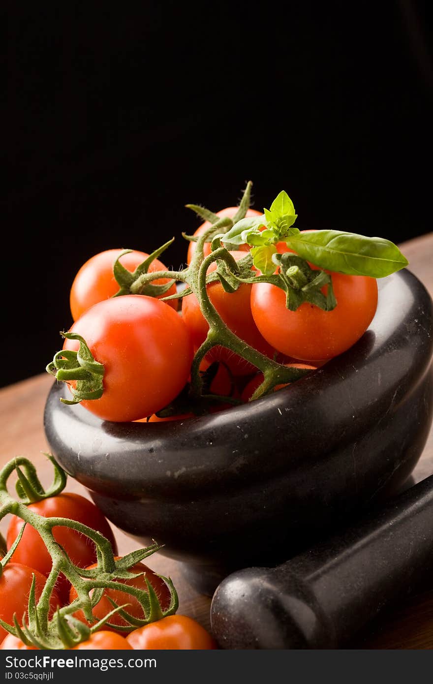 Photo of tomatoes inside a black mortar ready to be smashed for preparing tomatoe sauce