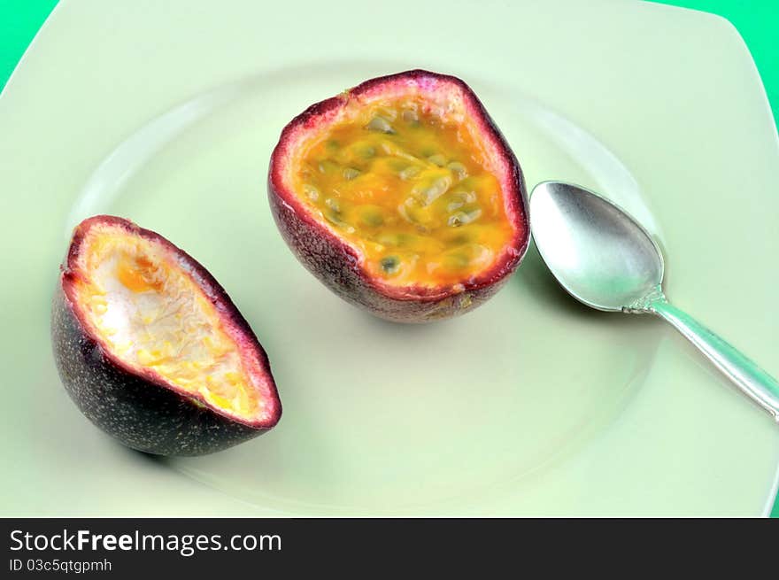 Sliced ​​ripe fruit Passiflora lies on the plate, and a number of small spoon. Sliced ​​ripe fruit Passiflora lies on the plate, and a number of small spoon