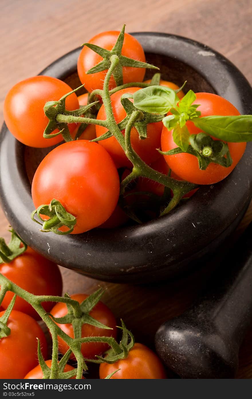 Photo of tomatoes inside a black mortar ready to be smashed for preparing tomatoe sauce