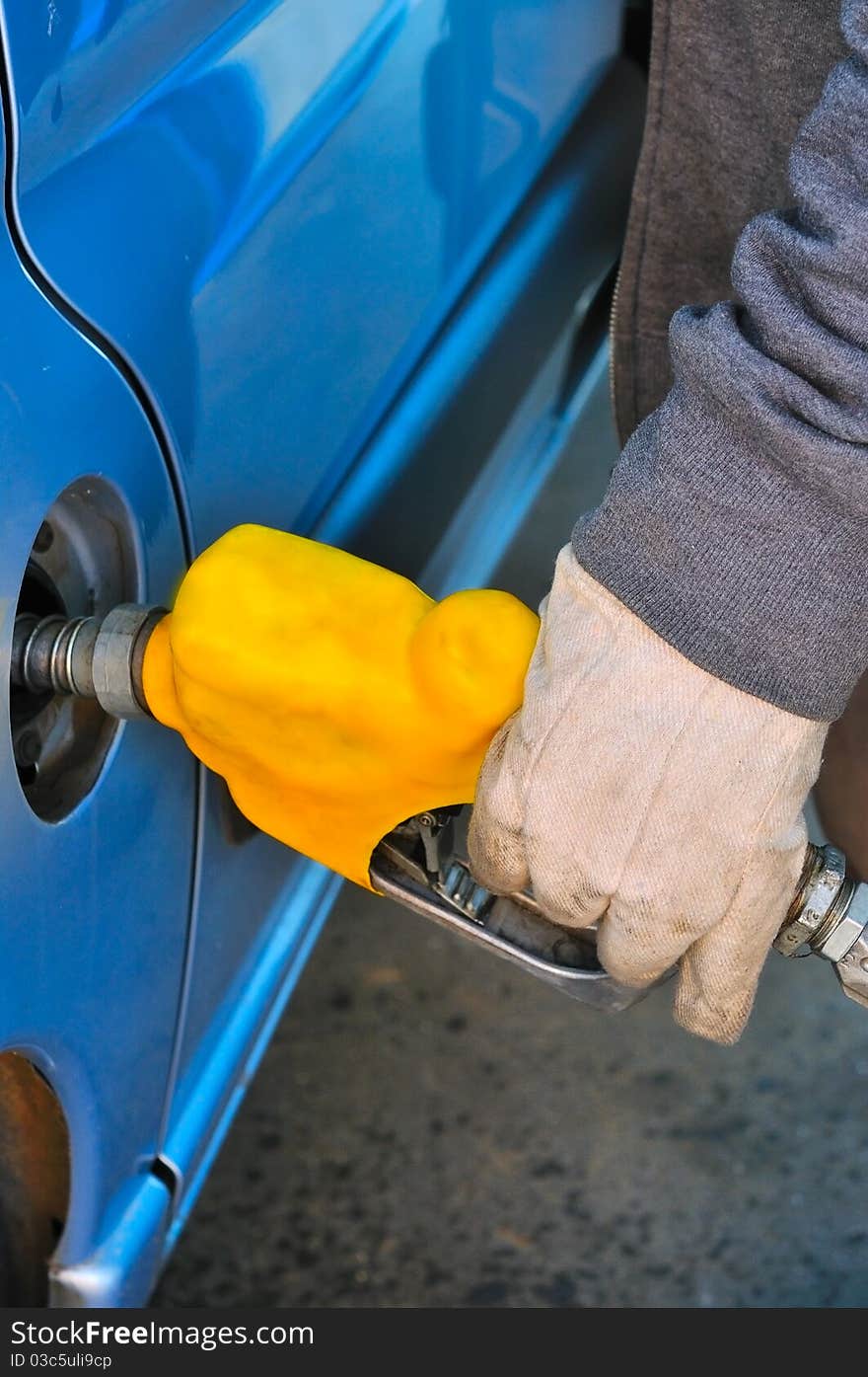 At the gas station worker fills a car diesel oil filling pistol yellow. At the gas station worker fills a car diesel oil filling pistol yellow