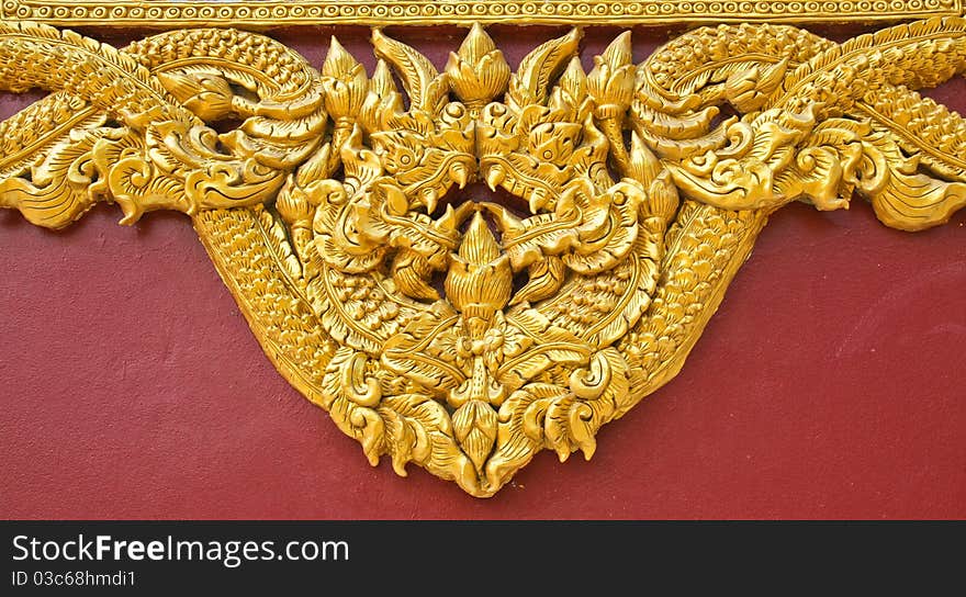 High relief sculpture, gold serpent on the floor of the temple wall. In northern Thailand